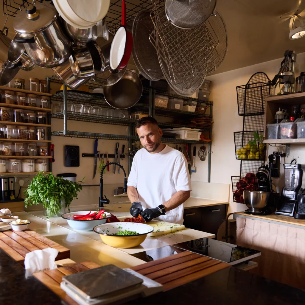 שף פרטי בתל אביב במעשנת השוק חותך פלפלים ועשבי תיבול טריים במטבח לאירוע יום הולדת
